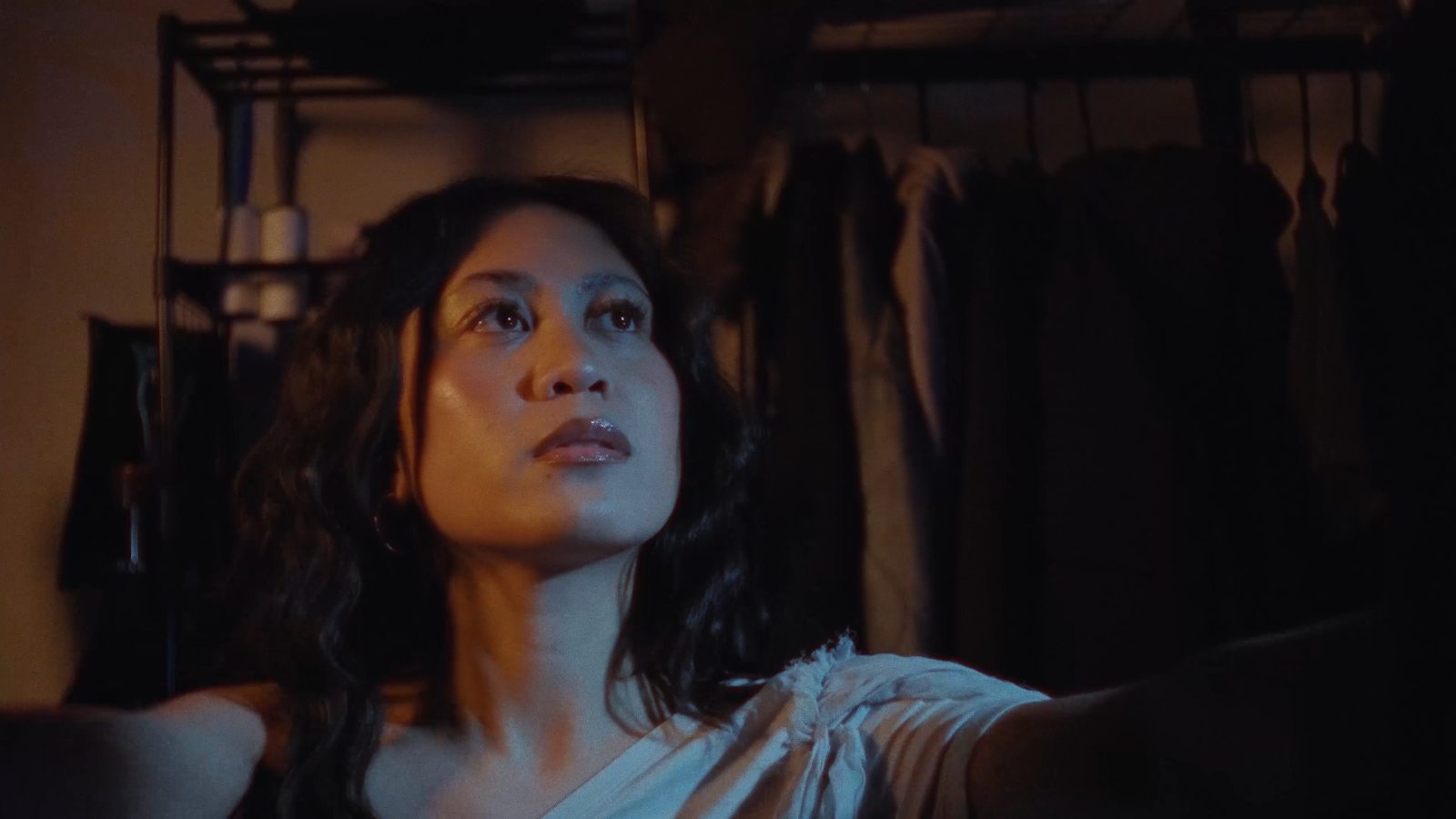 Frame from Elyssa Plaza, Charm: a woman looks up in warm low light
